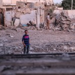 Un ragazzino cammina tra le macerie di Douma Un ragazzino cammina tra le macerie di Douma