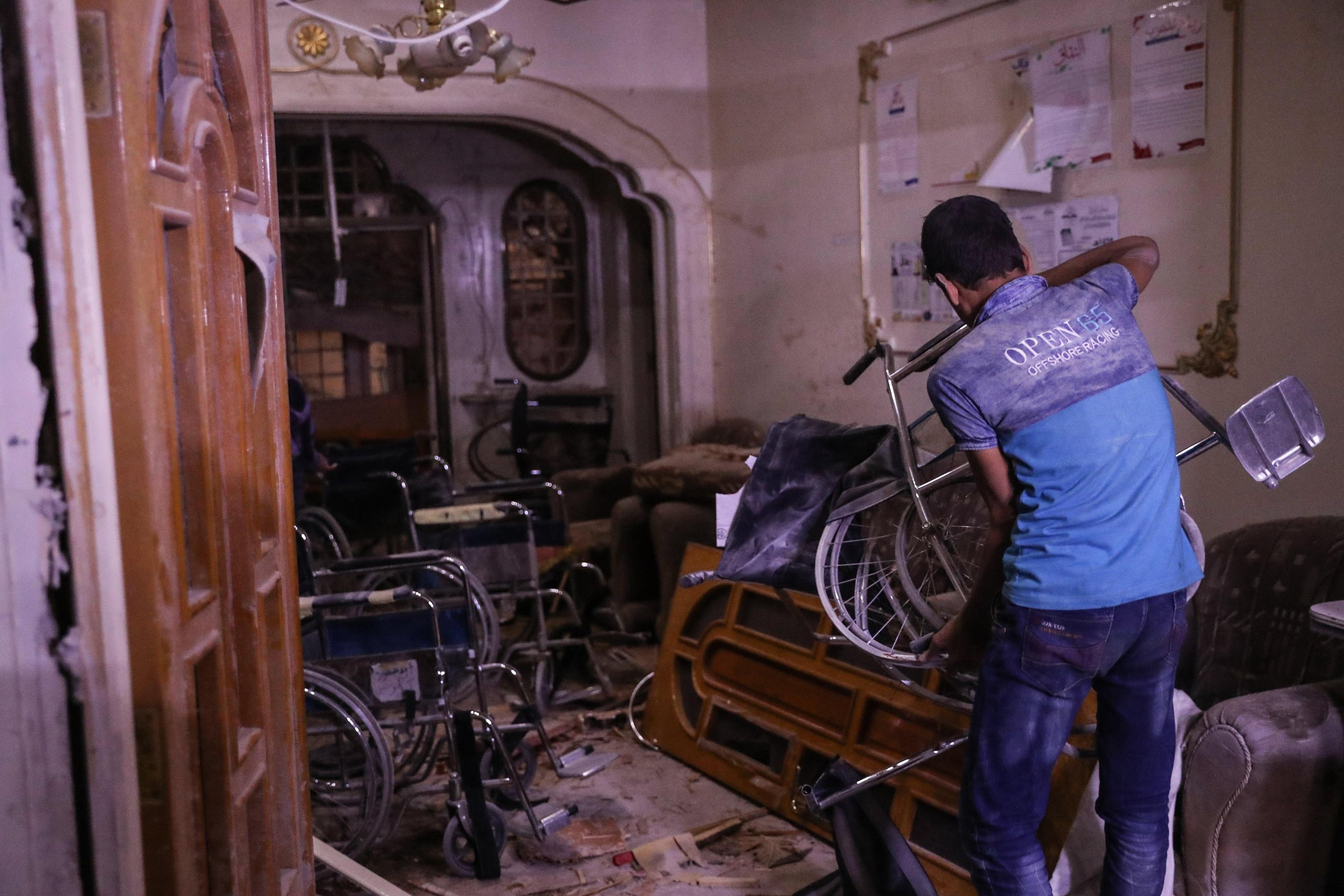 Un uomo solleva una delle sedie a rotelle che si trova all'interno del centro colpito dalla bomba Un uomo solleva una delle sedie a rotelle che si trova all'interno del centro colpito dalla bomba