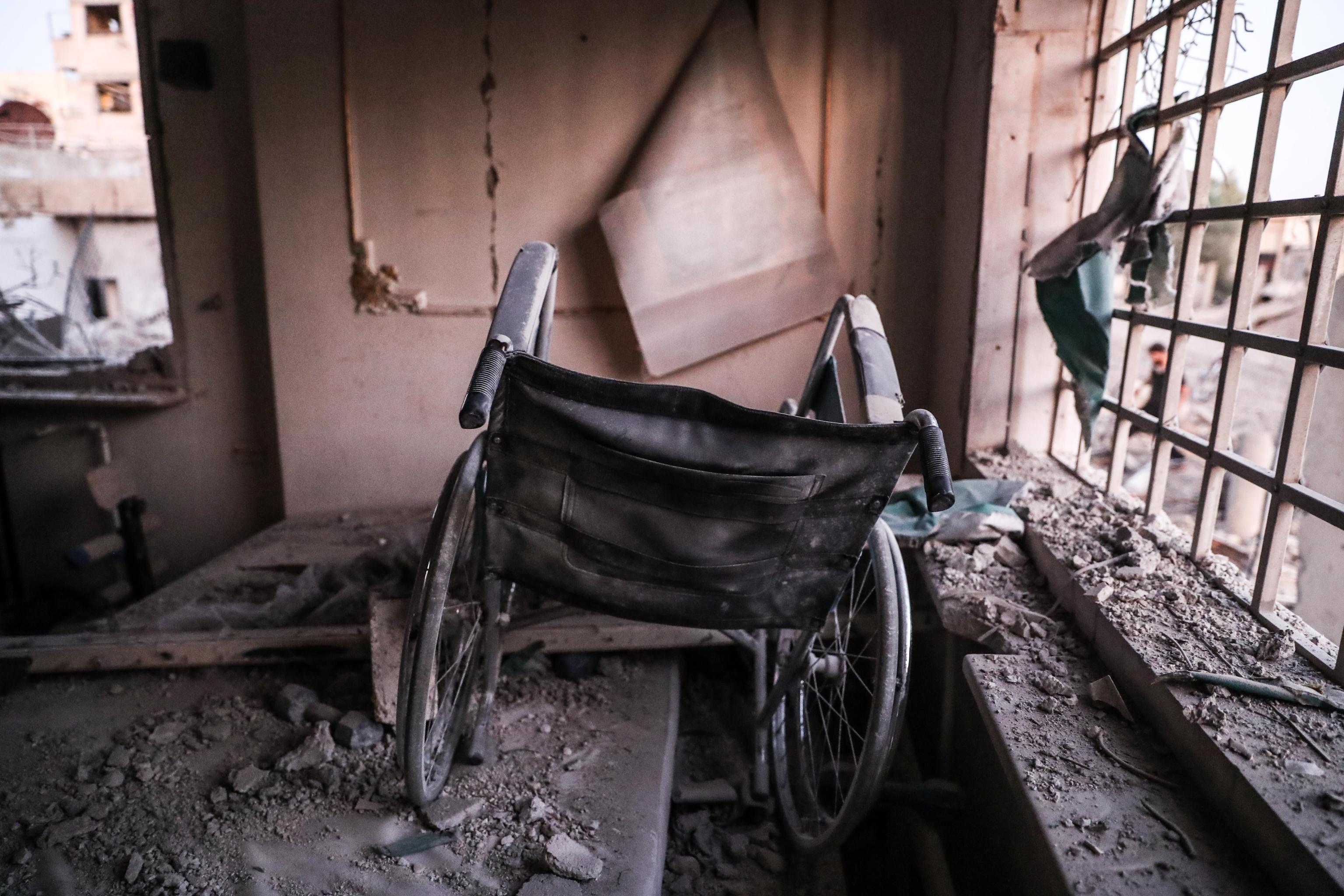 Tra i resti del centro, il primo piano di una sedia a rotelle danneggiata Tra i resti del centro, il primo piano di una sedia a rotelle danneggiata