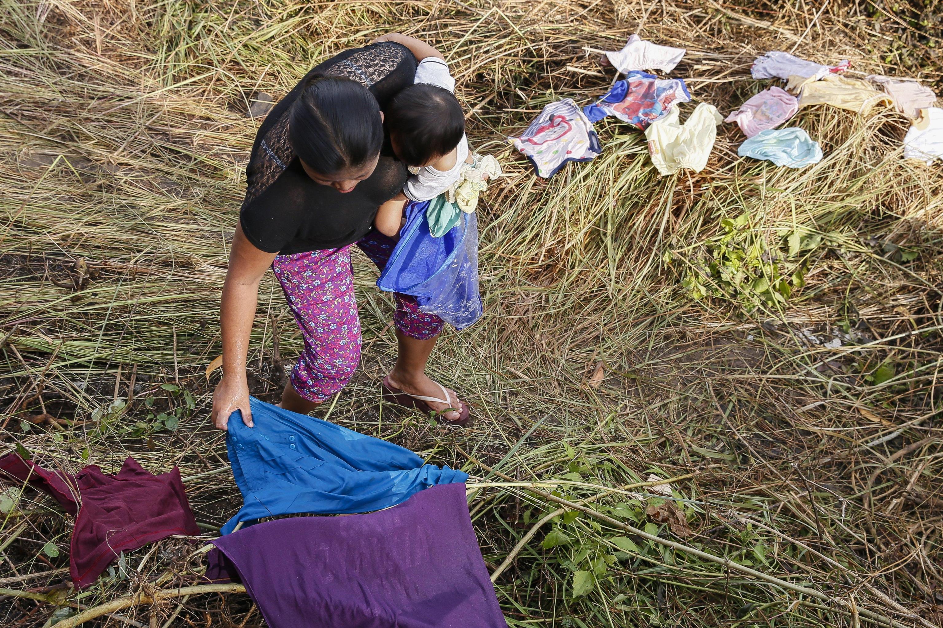 Una donna con il figlio stende e prepara la biancheria nel villaggio di Datah
