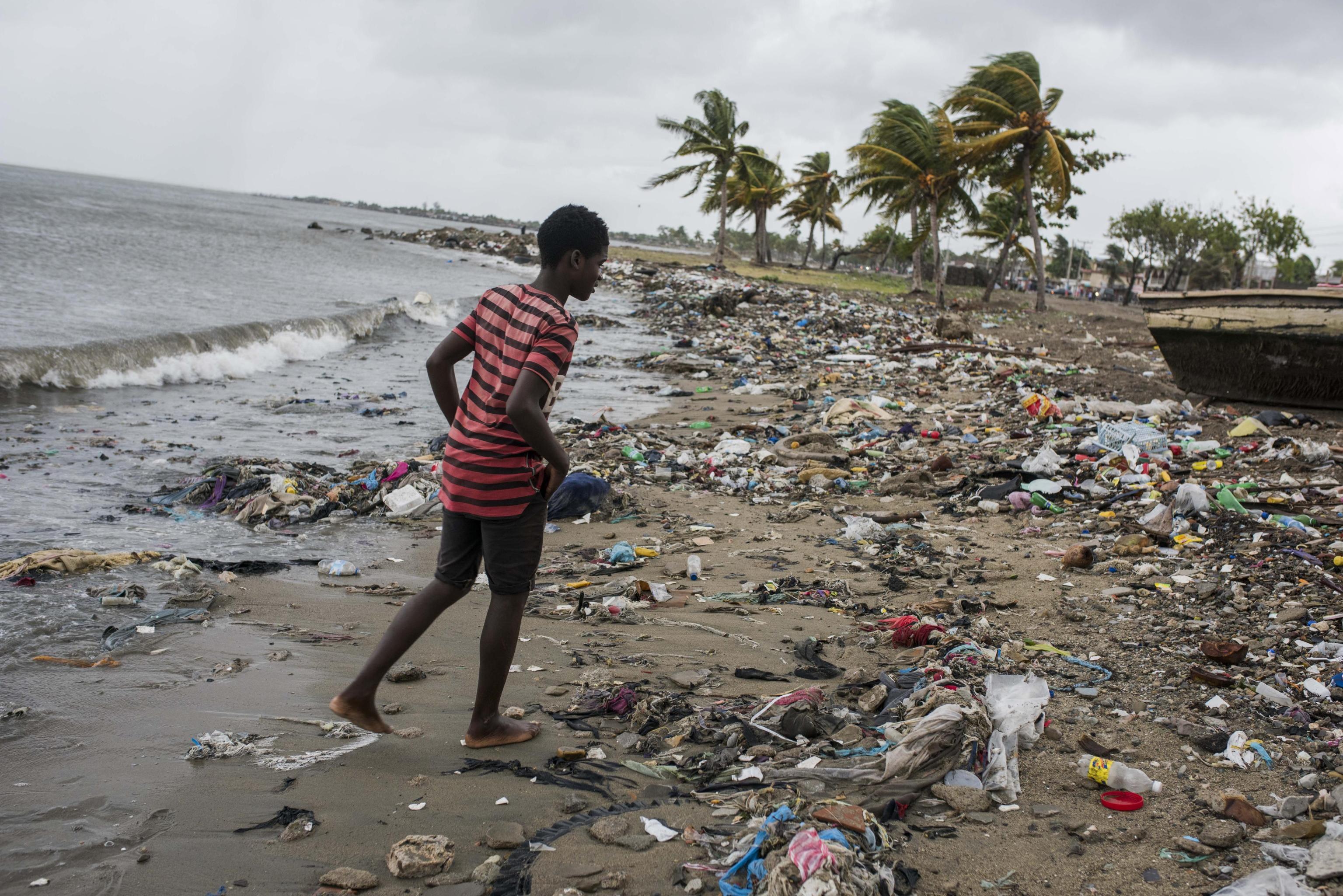 Cap Haitian, Haiti. Ragazzo su una spiaggia ricoperta da detriti Cap Haitian, Haiti. Ragazzo su una spiaggia ricoperta da detriti