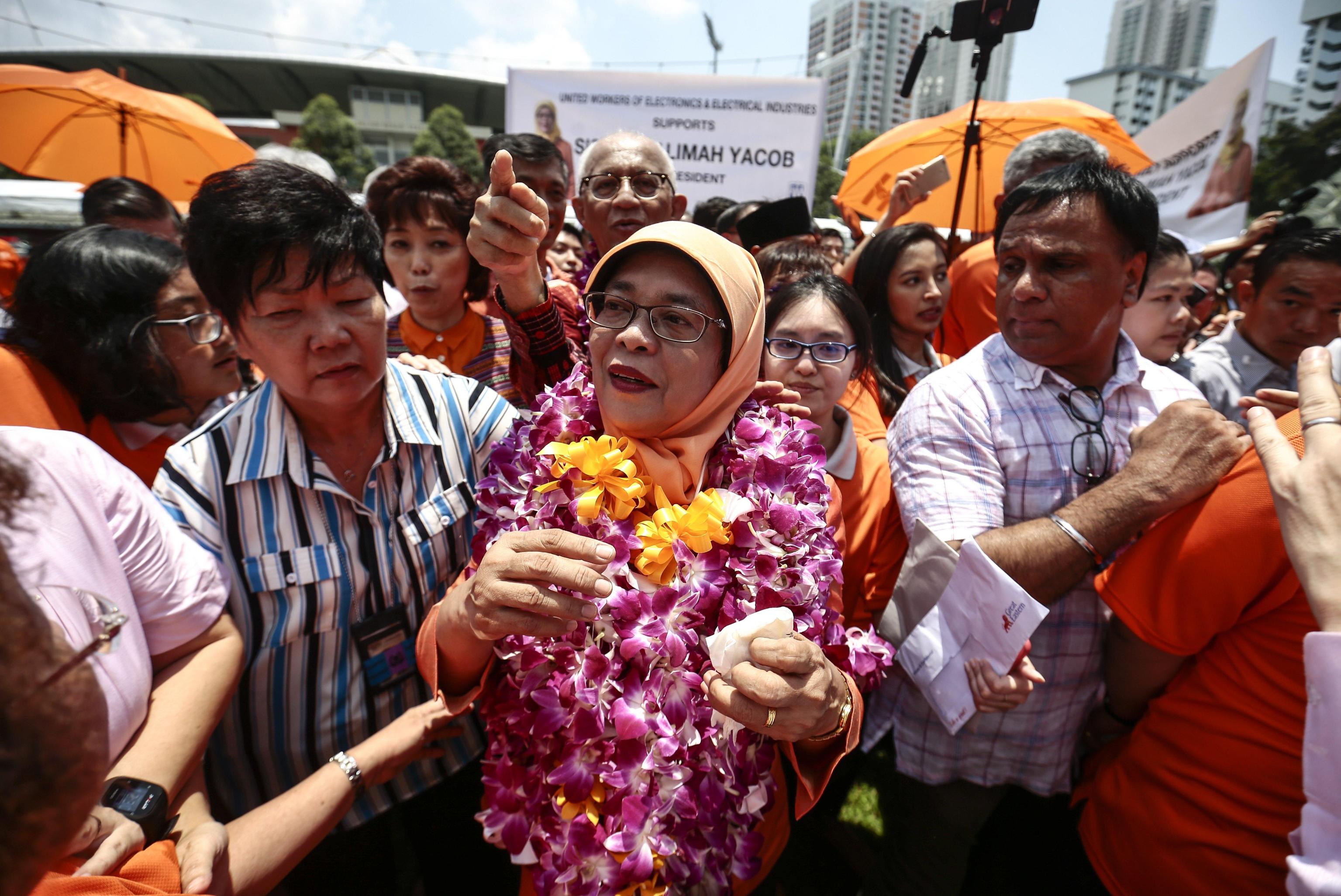 Halimah Yacob, circondata da una folla di sostenitori, si allontana dal nomination centre in Singapore