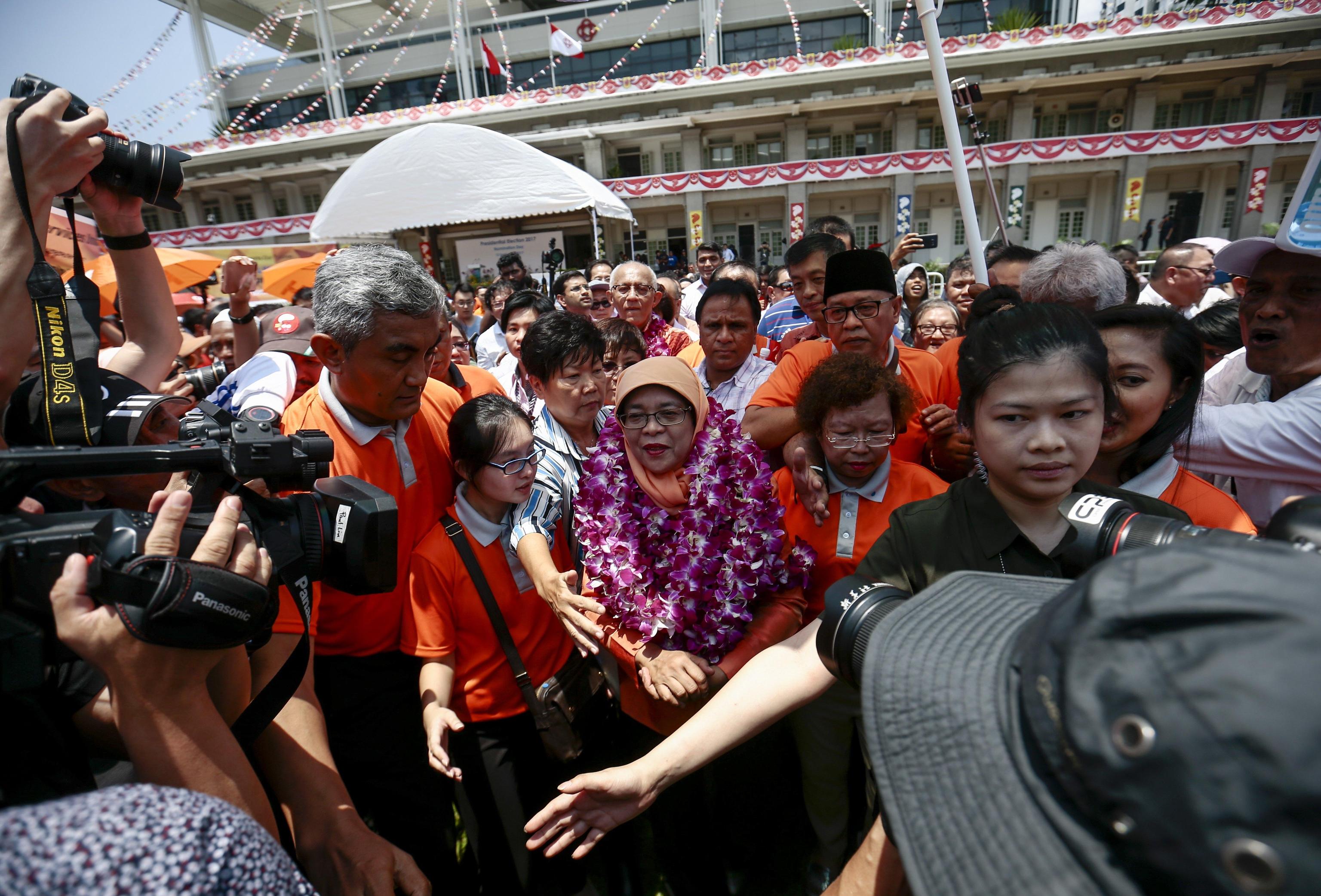 Halimah Yacob, circondata dal suo entourage e dalla security, incontra i suoi sostenitori dopo l'elezione