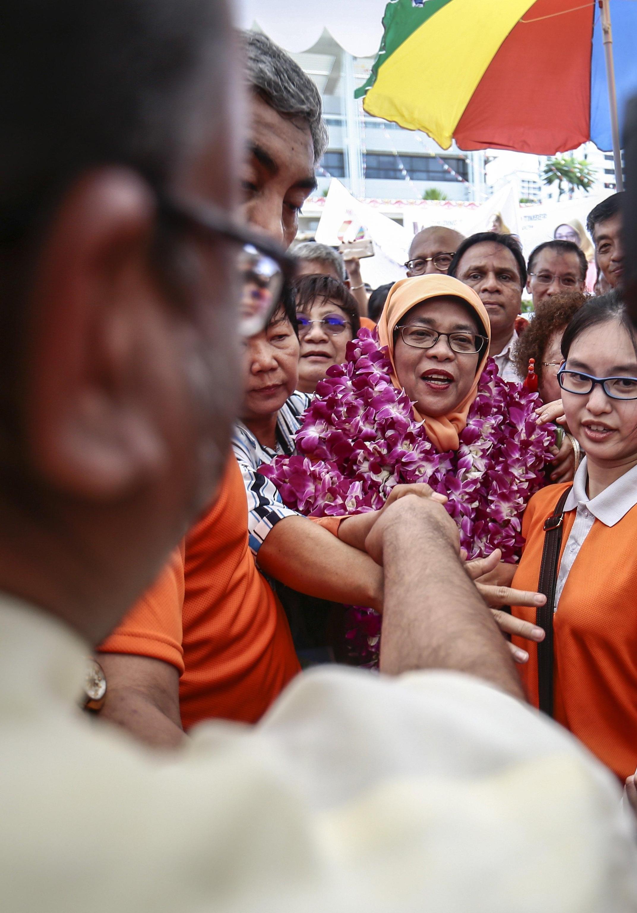 Halimah Yacob stringe la mano ad un sostenitore davanti al People's Association Centre.