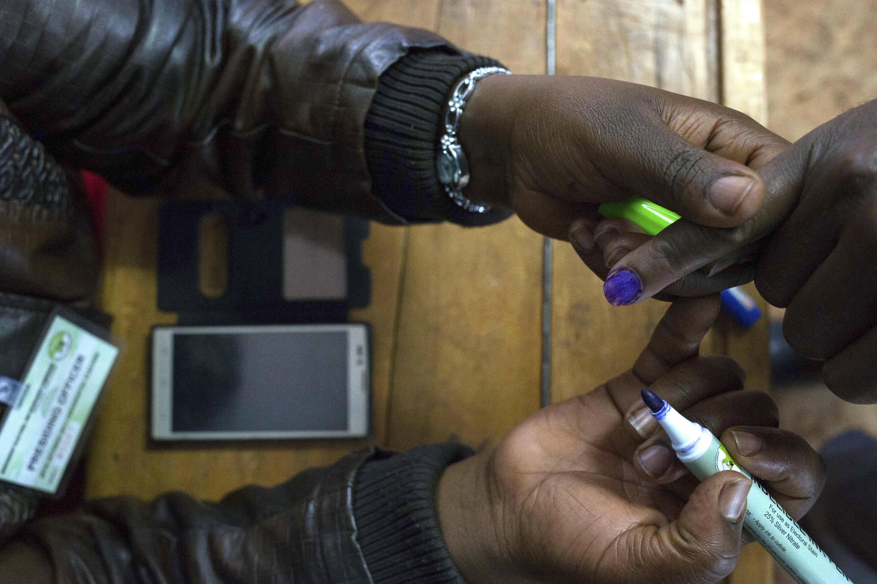 Un funzionario di segnalazione contrassegna il dito di un elettore con un segnalino alla stazione di voto di Mutomo della scuola elementare di Mutomo a Gatundu, Kenya Un funzionario di segnalazione contrassegna il dito di un elettore con un segnalino alla stazione di voto di Mutomo della scuola elementare di Mutomo a Gatundu, Kenya