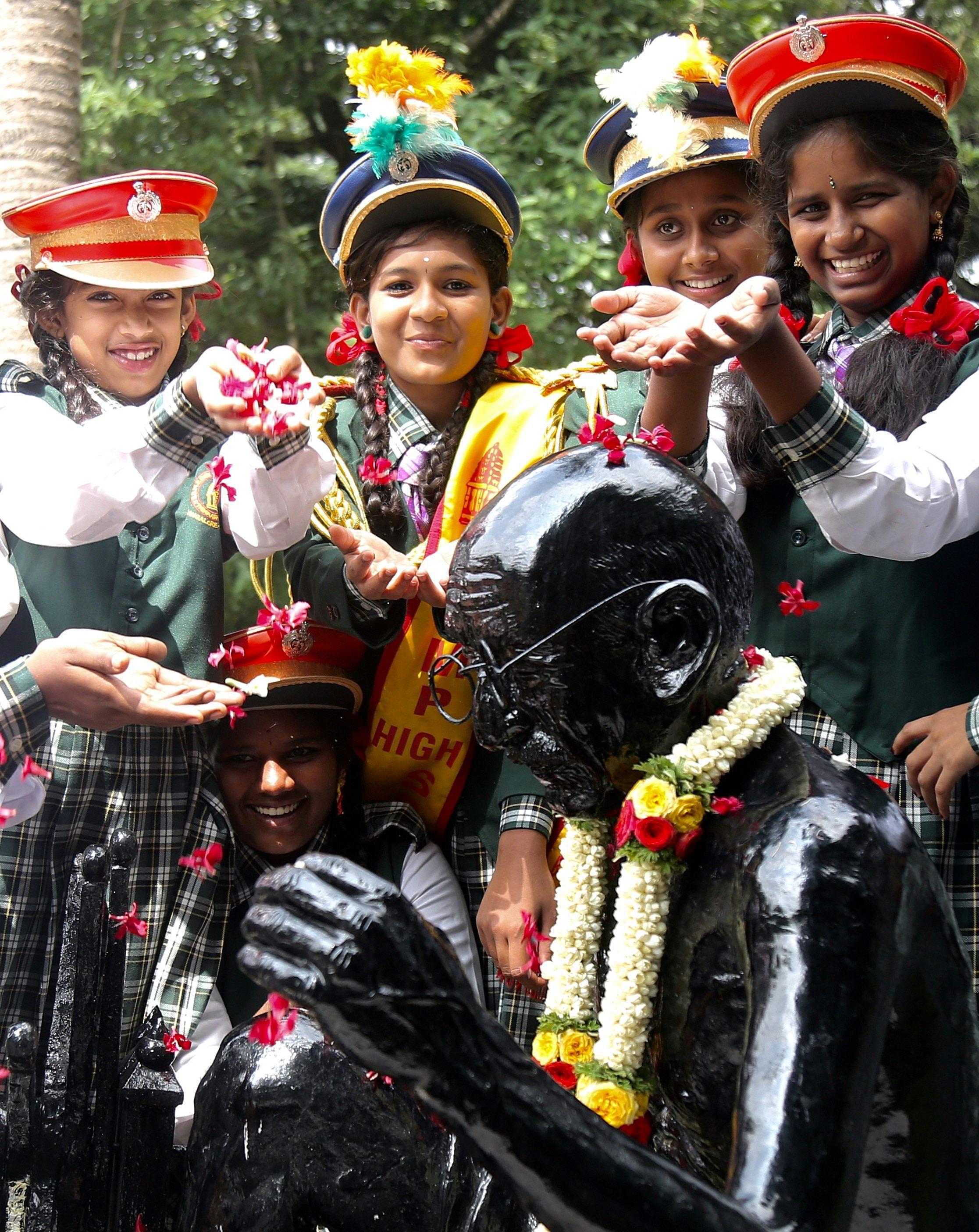 Un gruppo di studentesse depone dei fiori su una statua di Gandhi a Bangalore