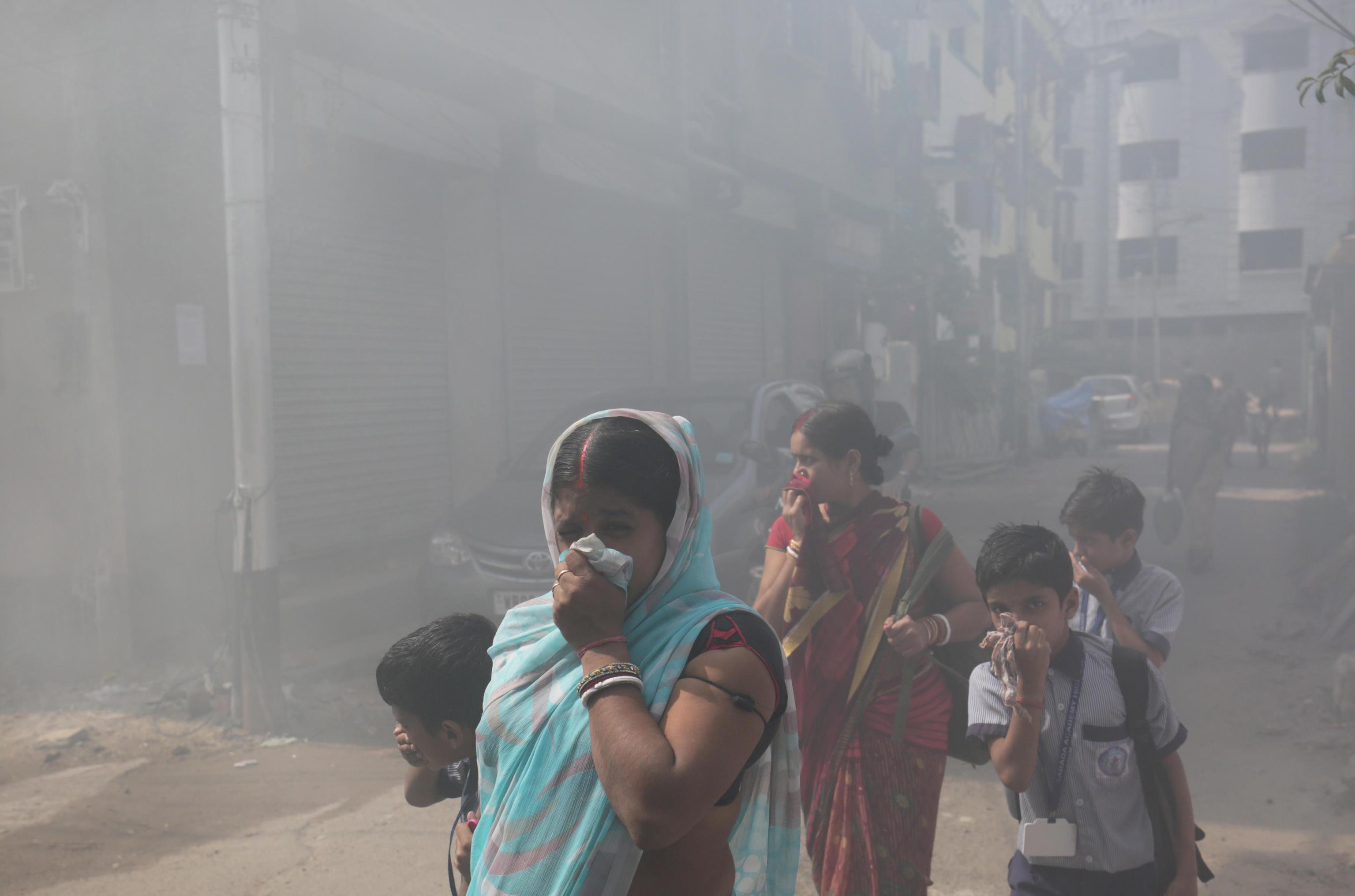 Cittadini a Calcutta camminano tra i fumi della disinfestazione