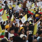 La folla che ha accolto il Pontefice, con bandiere del Myanmar e del Vaticano La folla che ha accolto il Pontefice, con bandiere del Myanmar e del Vaticano