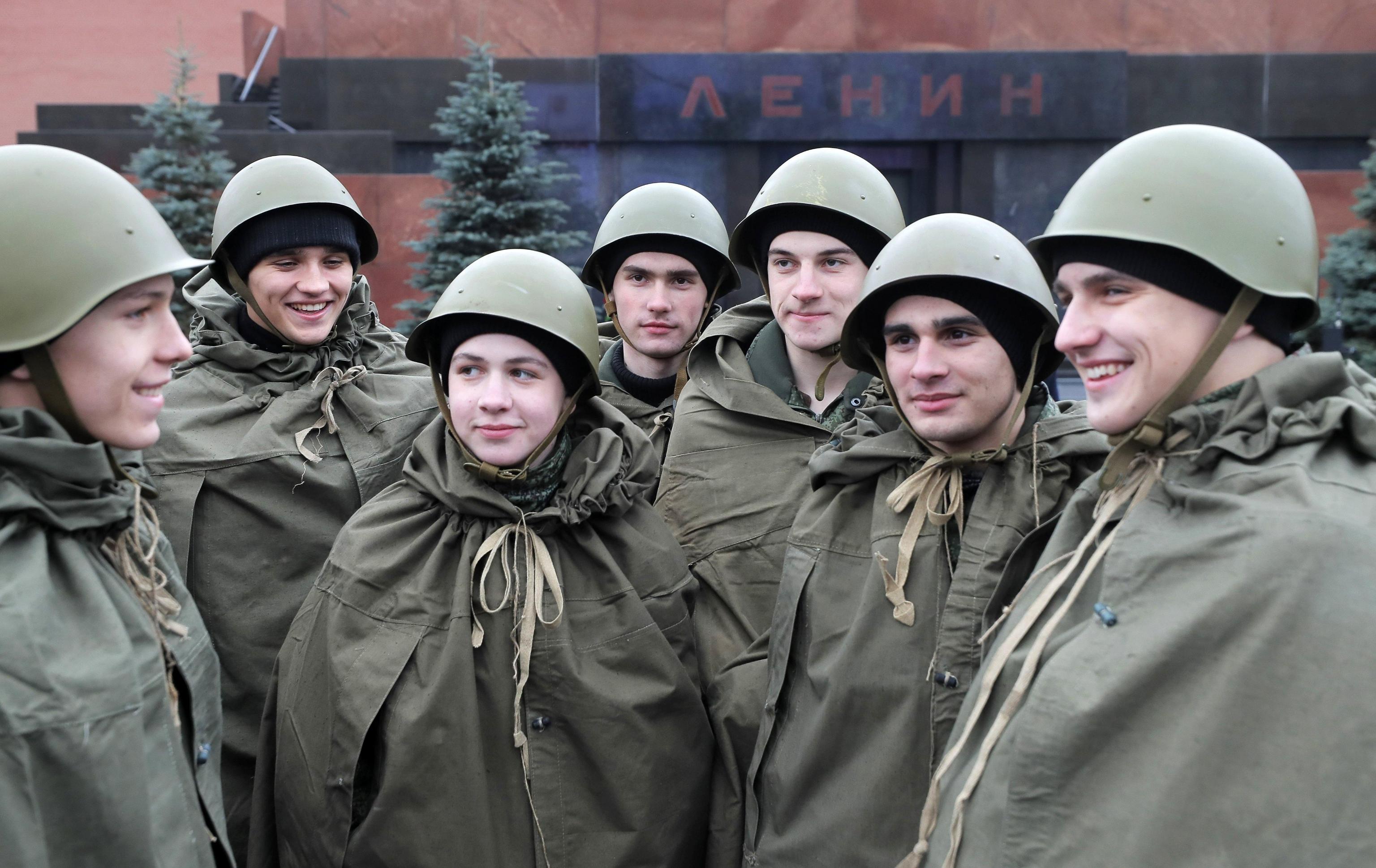 Giovani russi in divisa storica, con elmetto e pastrano per difendersi dalla pioggia