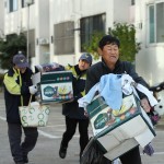 Un residente, aiutato dai soccorsi, porta via oggetti domestici dopo aver evacuato la sua casa