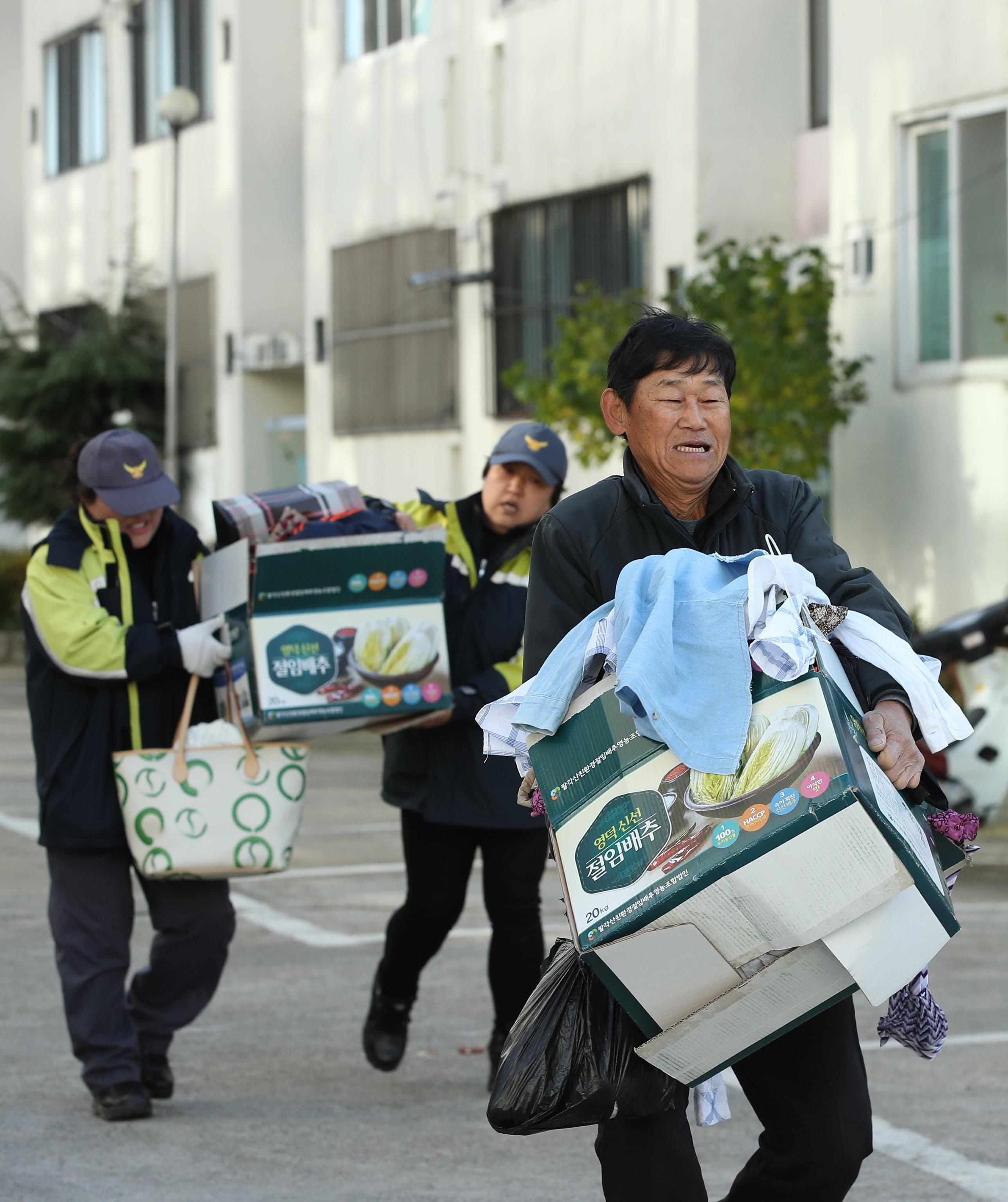 Un residente, aiutato dai soccorsi, porta via oggetti domestici dopo aver evacuato la sua casa Un residente, aiutato dai soccorsi, porta via oggetti domestici dopo aver evacuato la sua casa