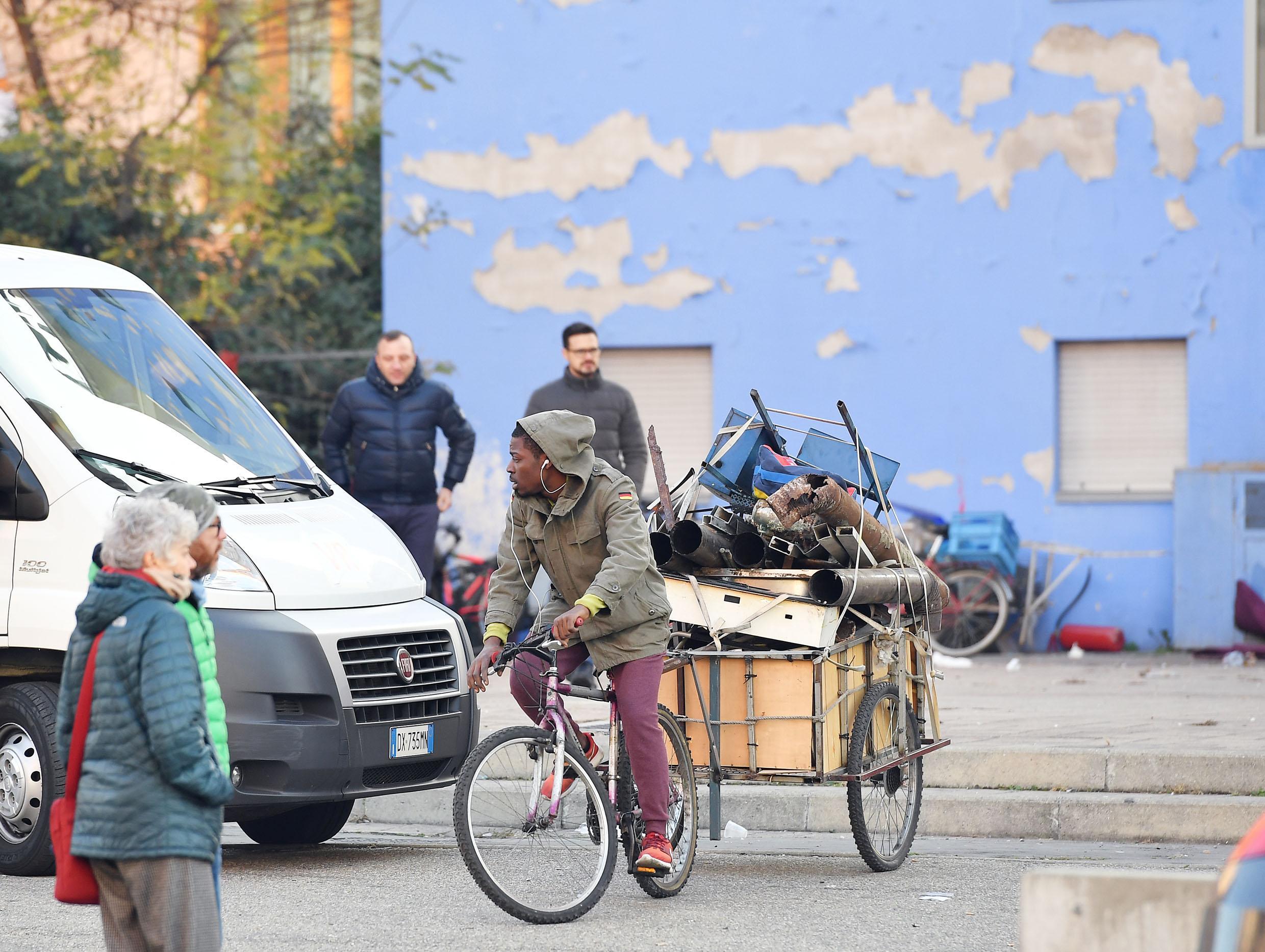 Un giovane di colore con una bicicletta e i suoi bagagli