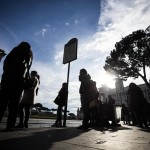 Alcune persone aspettano l'autobus alla fermata di Piazza Venezia a Roma