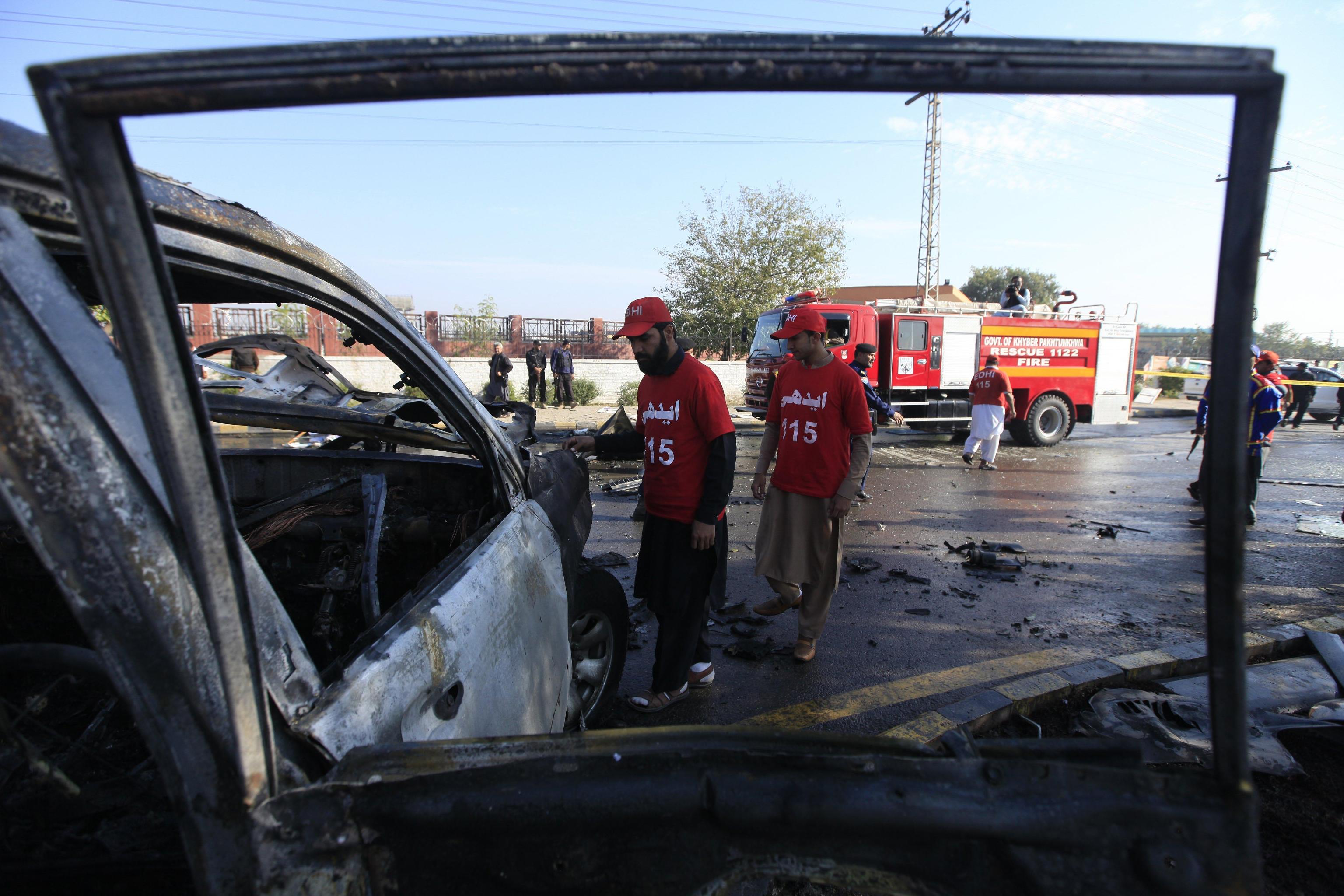 Gli ufficiali di sicurezza pakistani ispezionano i resti del veicolo sul quale viaggiavano l'agente di polizia e i suoi aiutanti