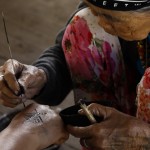 Whang-od all’opera mentre con un pennellino traccia la linea del tatuaggio