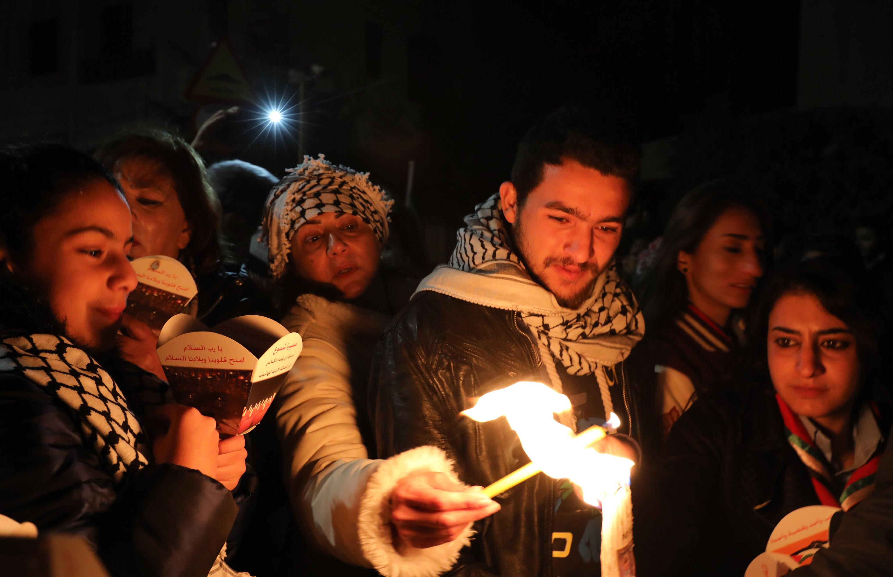 Alcuni fedeli giordani accendono le loro candele per prendere parte al corteo