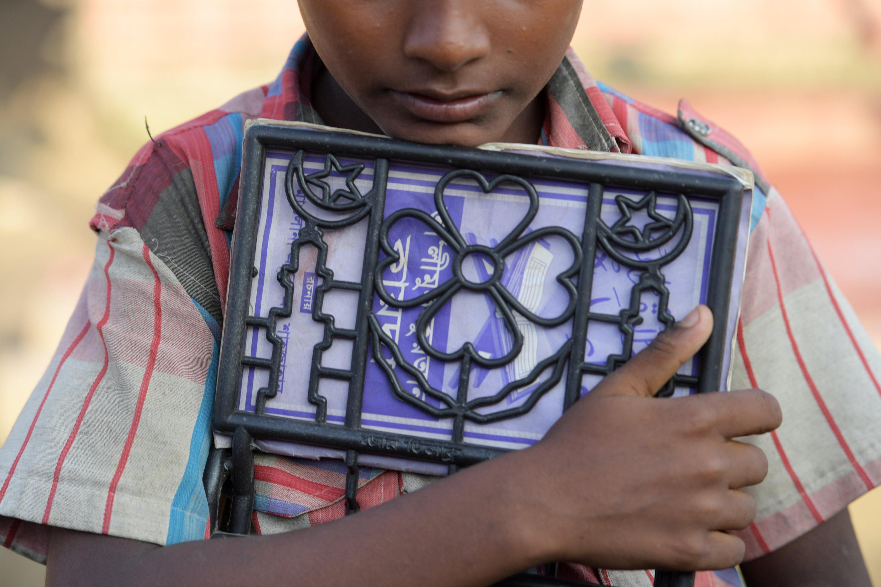 Un bambino Rohingya tiene stretto un testo scolastico al campo profughi di Jamtoli, vicino Cox's Bazar