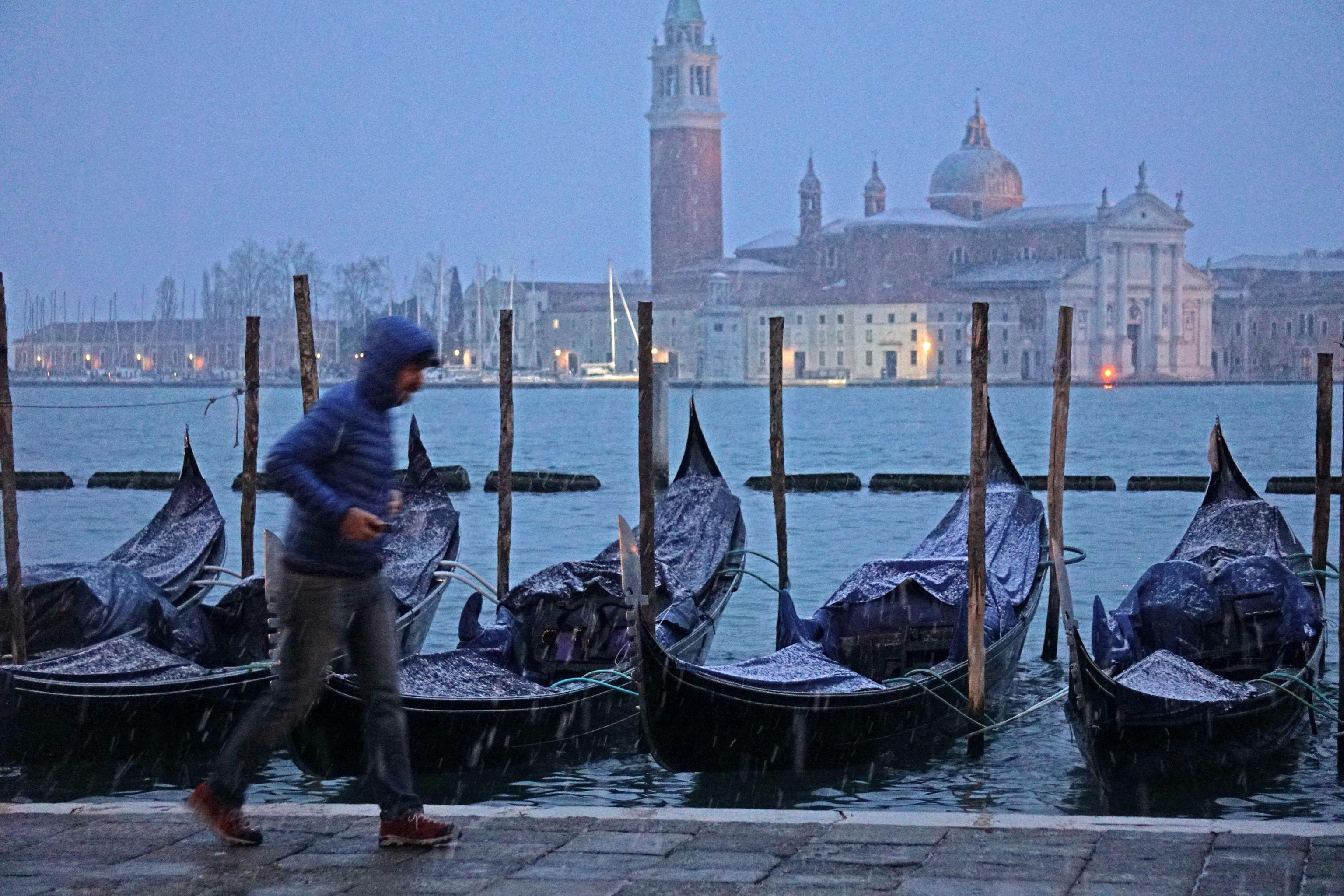 Uomo corre sotto la neve sul lungomare veneziano