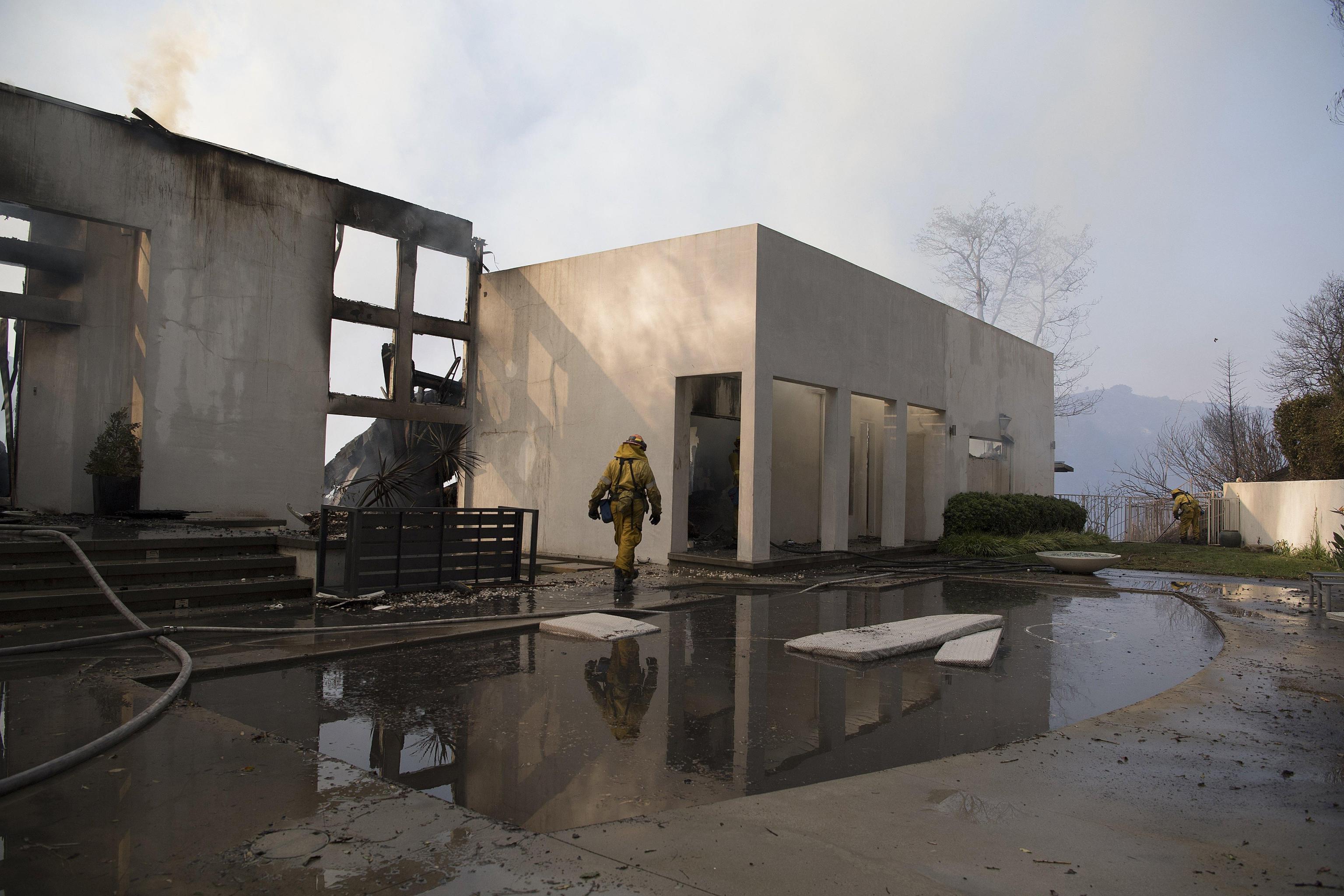 Un pompiere cammina fra le macerie di una villa distrutta a Bel Air, California