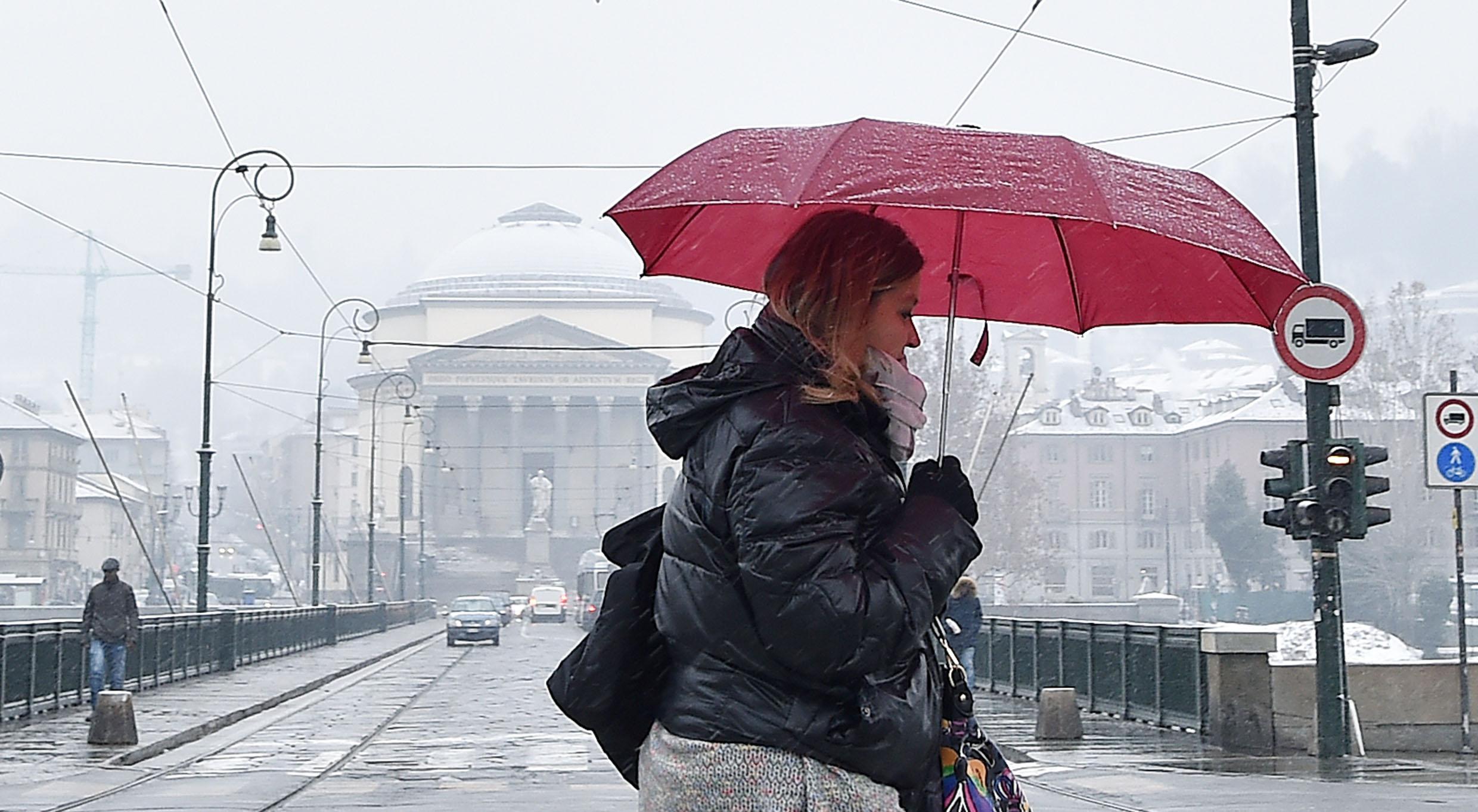 Passante cerca di proteggersi dalla neve con un ombrello