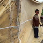 Un bambino sta fuori dalla tenda usata come cucina nel suo rifugio ad al-Ashari Un bambino sta fuori dalla tenda usata come cucina nel suo rifugio ad al-Ashari