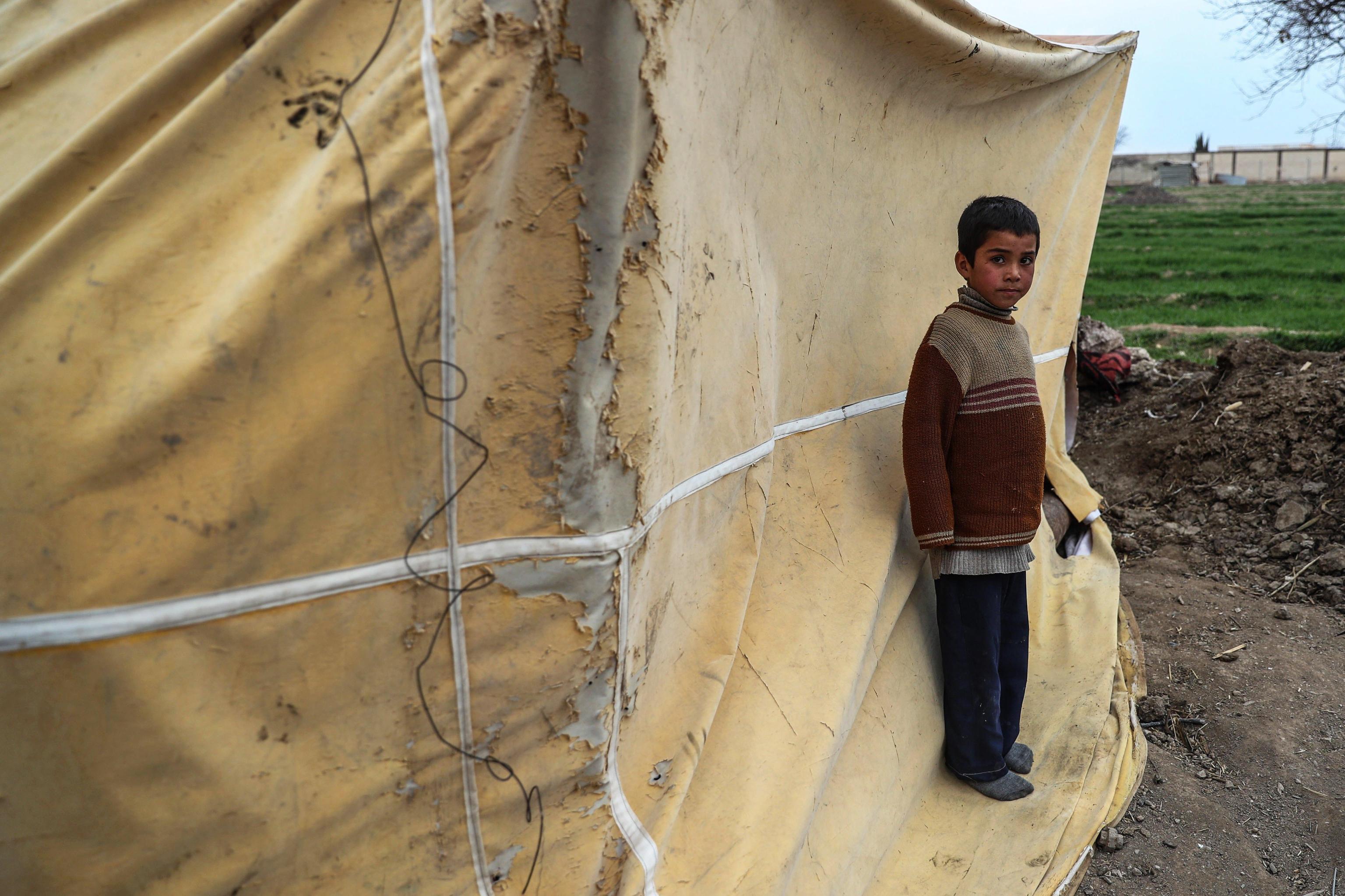 Un bambino sta fuori dalla tenda usata come cucina nel suo rifugio ad al-Ashari Un bambino sta fuori dalla tenda usata come cucina nel suo rifugio ad al-Ashari