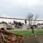 Uno sfollato siriano stende i panni. Alle sue spalle quello che rimane di al-Asha'ari city Uno sfollato siriano stende i panni. Alle sue spalle quello che rimane di al-Asha'ari city