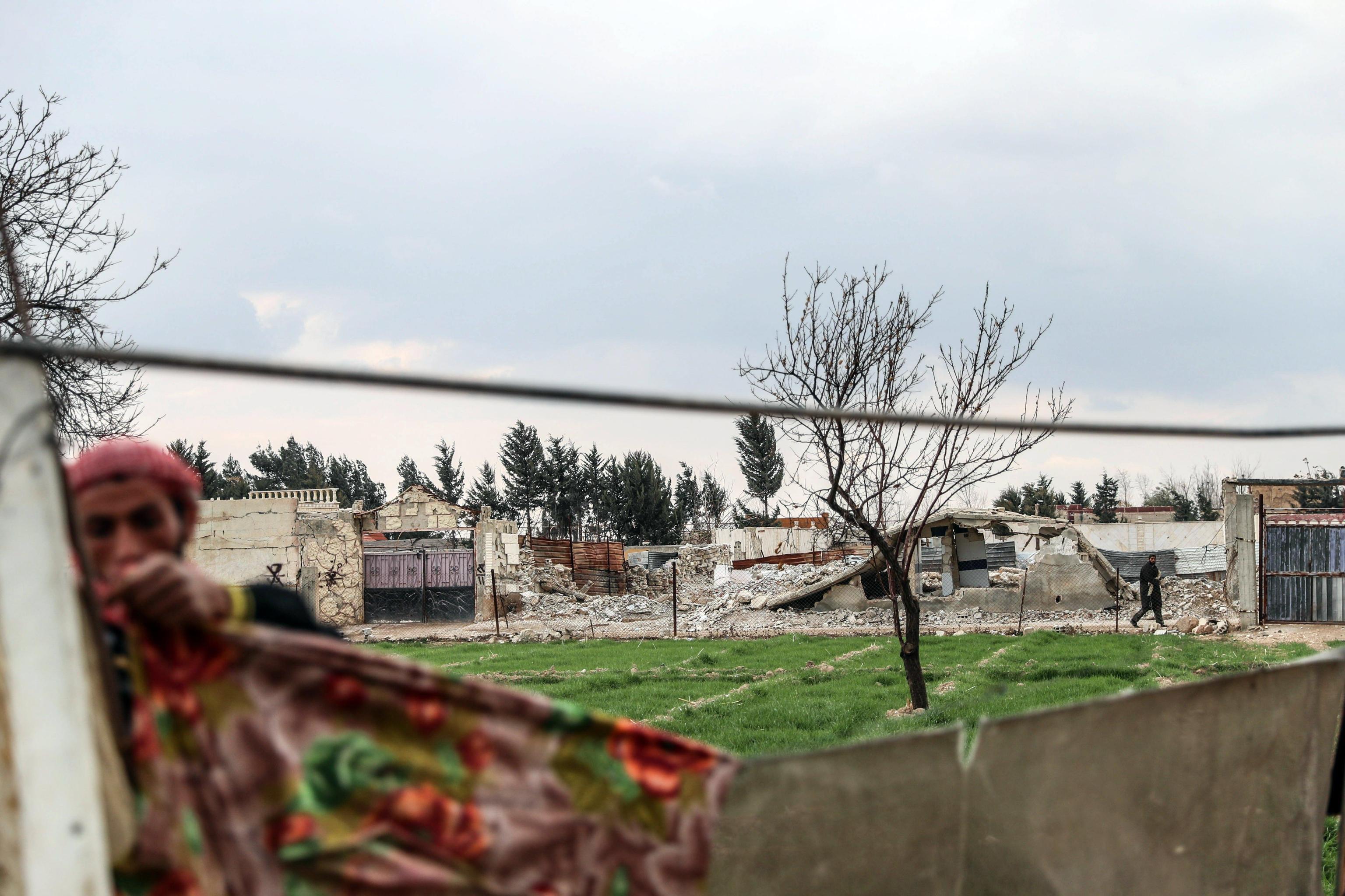 Uno sfollato siriano stende i panni. Alle sue spalle quello che rimane di al-Asha'ari city Uno sfollato siriano stende i panni. Alle sue spalle quello che rimane di al-Asha'ari city