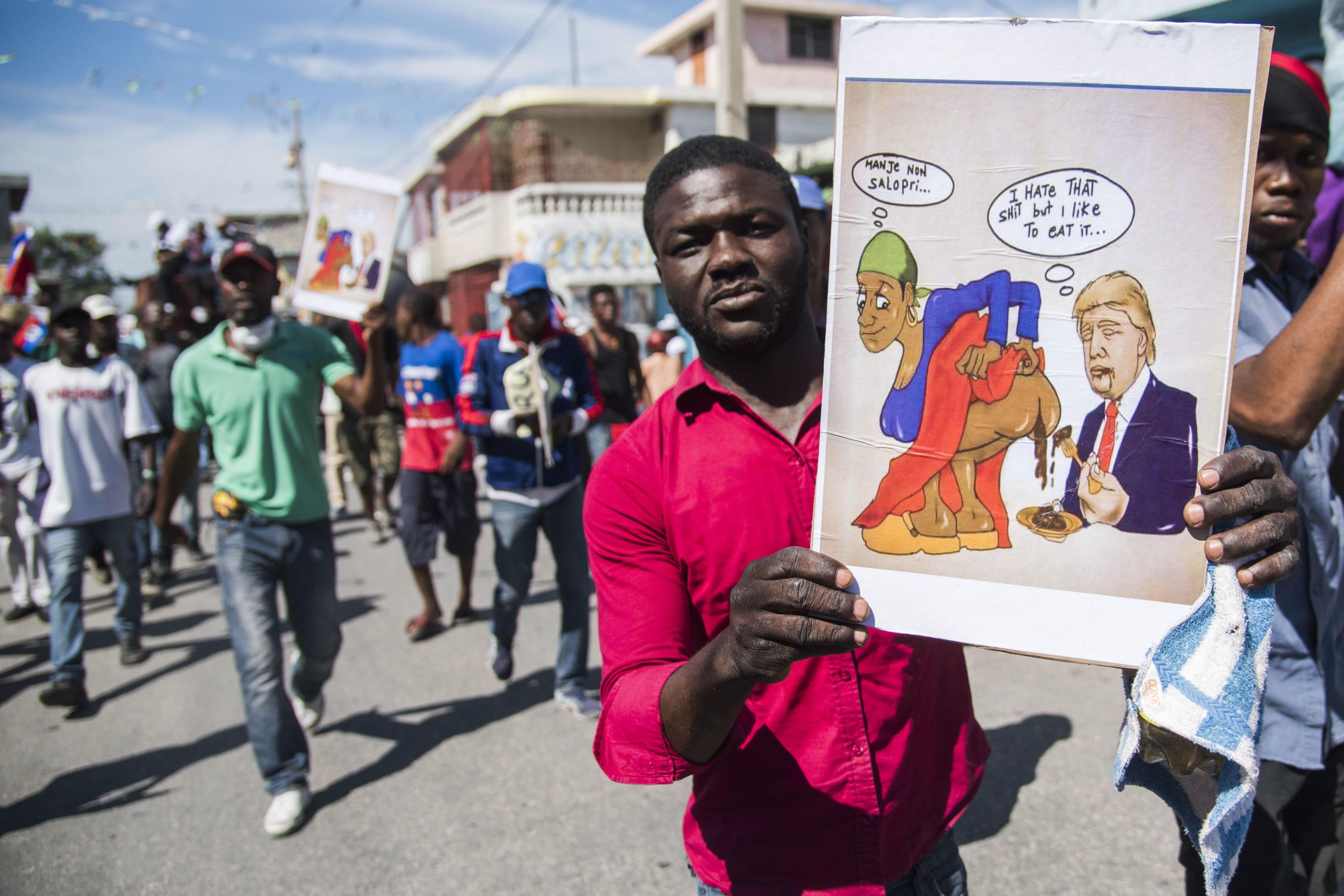 Un manifestante tiene in mano una vignetta provocatoria verso Trump Un manifestante tiene in mano una vignetta provocatoria verso Trump