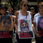 Parenti mostrano i cartelli con i visi dei loro morti