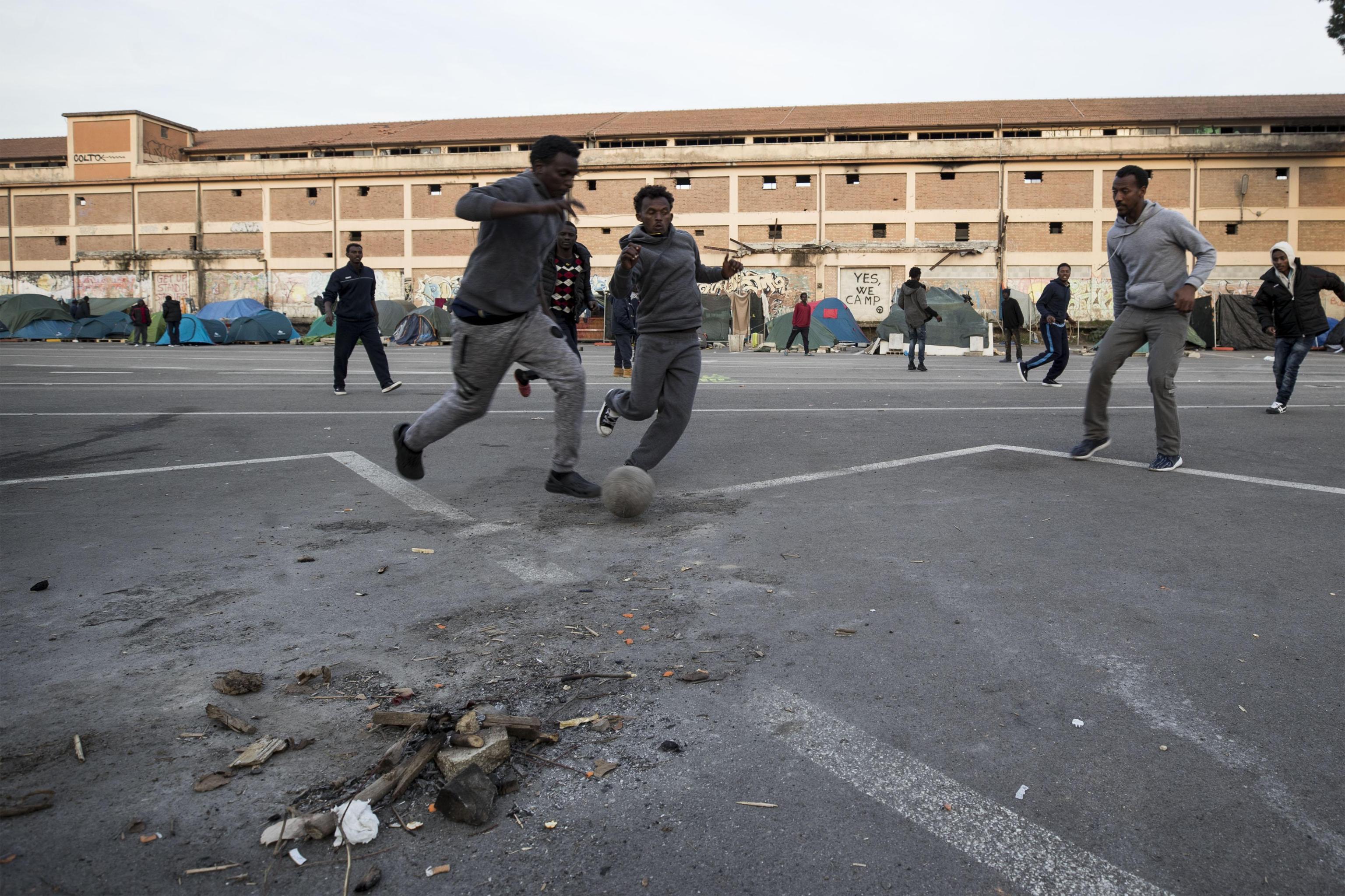Migranti che giocano a pallone nella tendopoli a Tiburtina Migranti che giocano a pallone nella tendopoli a Tiburtina