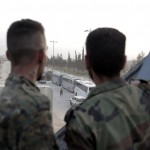 I soldati siriani guardano una linea di autobus noleggiati dal governo