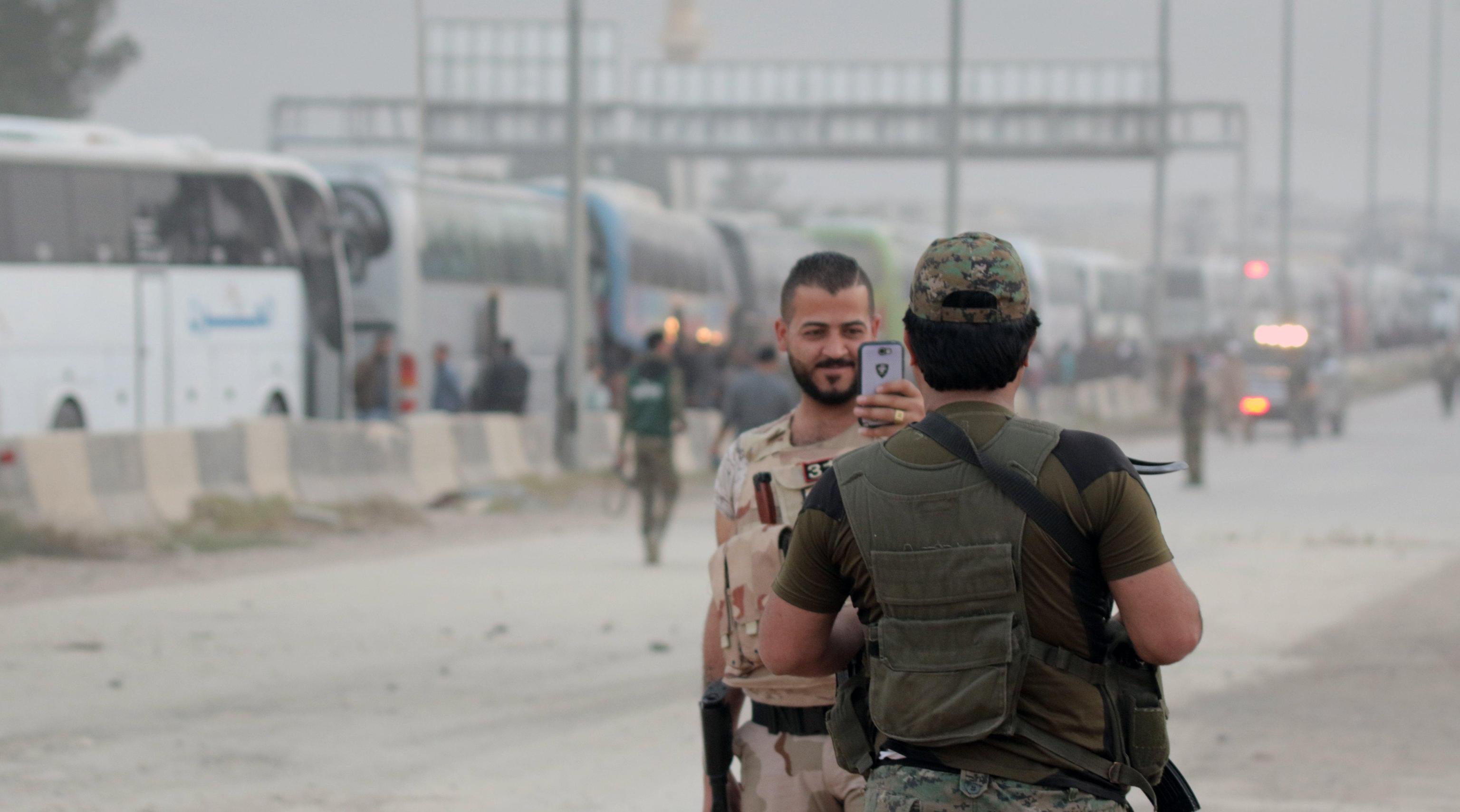 I soldati siriani posano per fotografie di fronte a una linea di autobus noleggiati dal governo