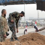 Soldati siriani posizionano piccole bandiere su un cumulo di terra, in attesa di partire