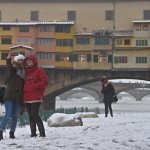 Due turiste si fanno un selfie davanti a Ponte Vecchio, completamente imbiancato dalla neve