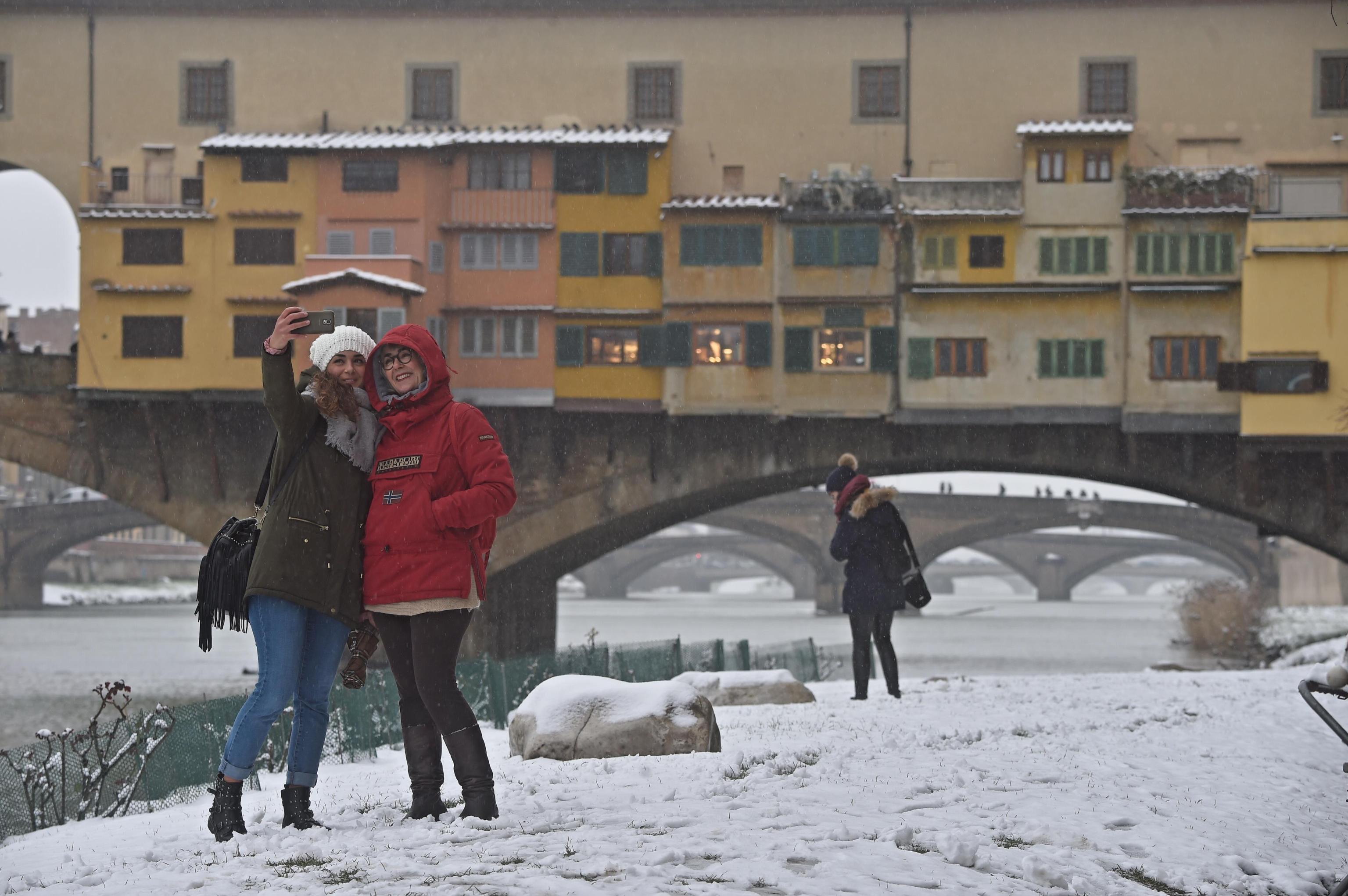 Due turiste si fanno un selfie davanti a Ponte Vecchio, completamente imbiancato dalla neve