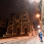 Una ragazza cammina sotto la neve in Piazza San Lorenzo a Genova, sullo sfondo si può ammirare la splendida cattedrale gotica di San Lorenzo