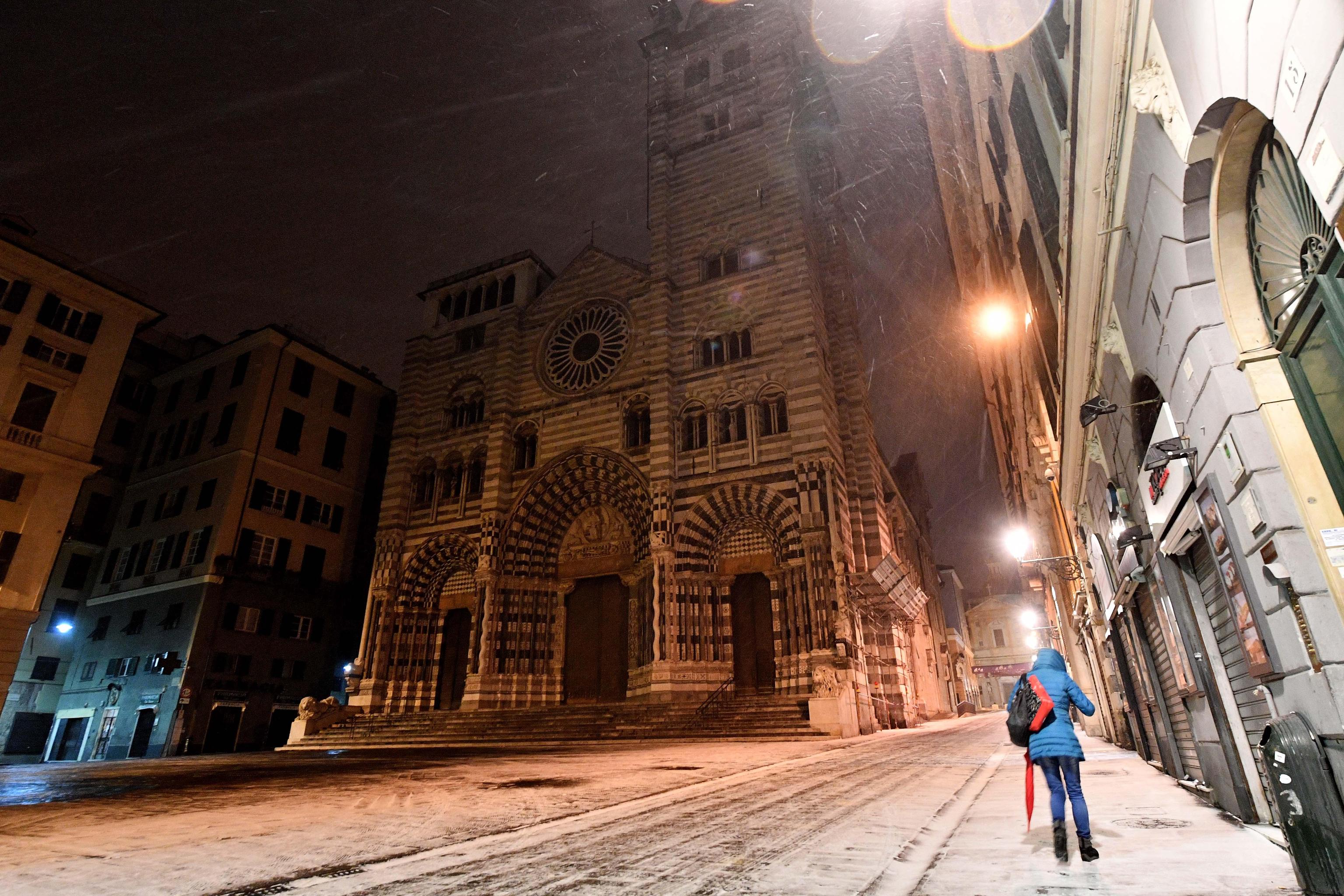 Una ragazza cammina sotto la neve in Piazza San Lorenzo a Genova, sullo sfondo si può ammirare la splendida cattedrale gotica di San Lorenzo