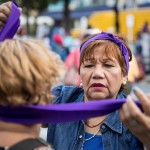 Una donna aiuta un’altra nel mettersi una fascia durante le manifestazioni di Caracas, in Venezuela