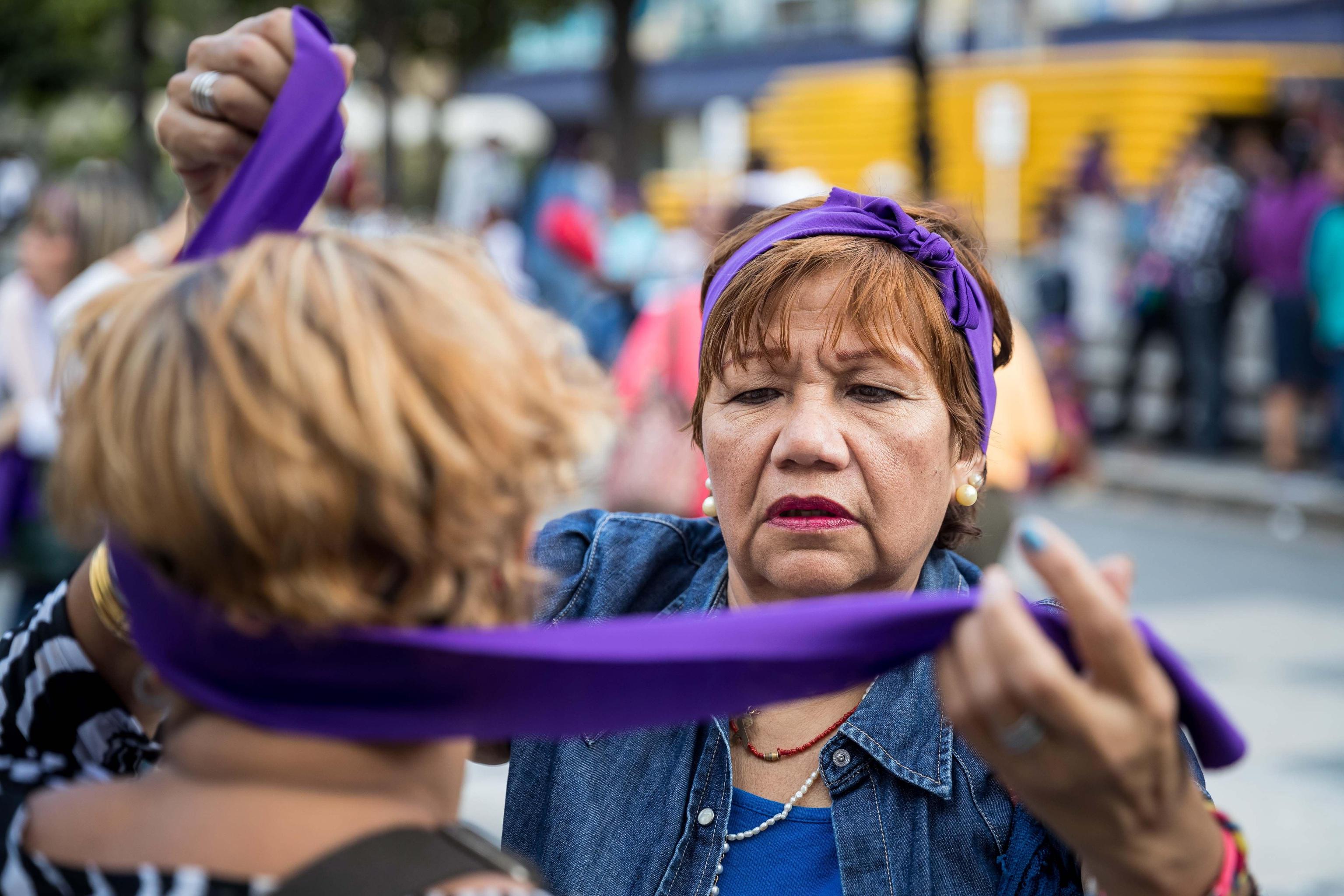 Una donna aiuta un’altra nel mettersi una fascia durante le manifestazioni di Caracas, in Venezuela