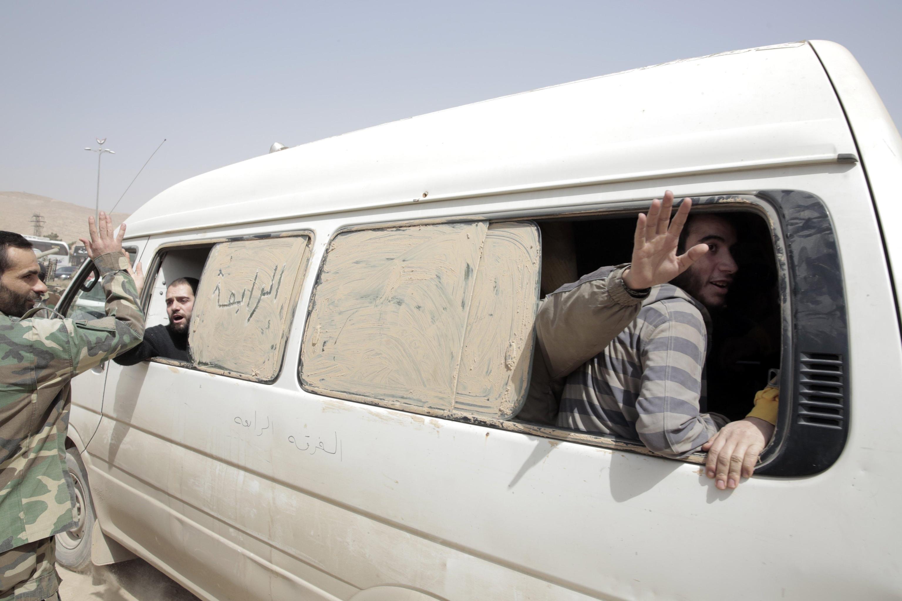 Alcuni soldati siriani siedono su un furgone dopo essere stati liberati dai combattenti ribelli nelle campagne di Damasco