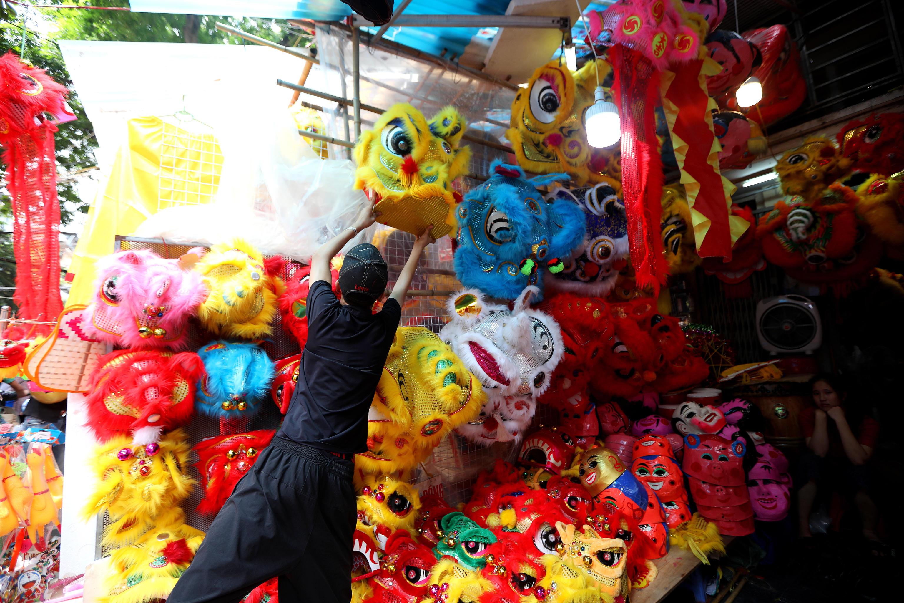 Un ragazzo appende una testa di dragone danzante nella via Hang Ma ad Hanoi. Il Mid-Autumn Festival è un festival del raccolto celebrato in particolare dai popoli cinese e vietnamita. Il festival si svolge il 15° giorno dell'8° mese del calendario lunare con la luna piena di notte,