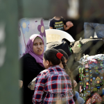 Una donna attende fra i pacchi e i bagagli nella zona della Sport City di Beirut