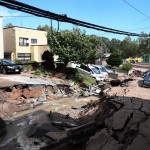Macchine coperte dal fango in una strada distrutta dal terremoto