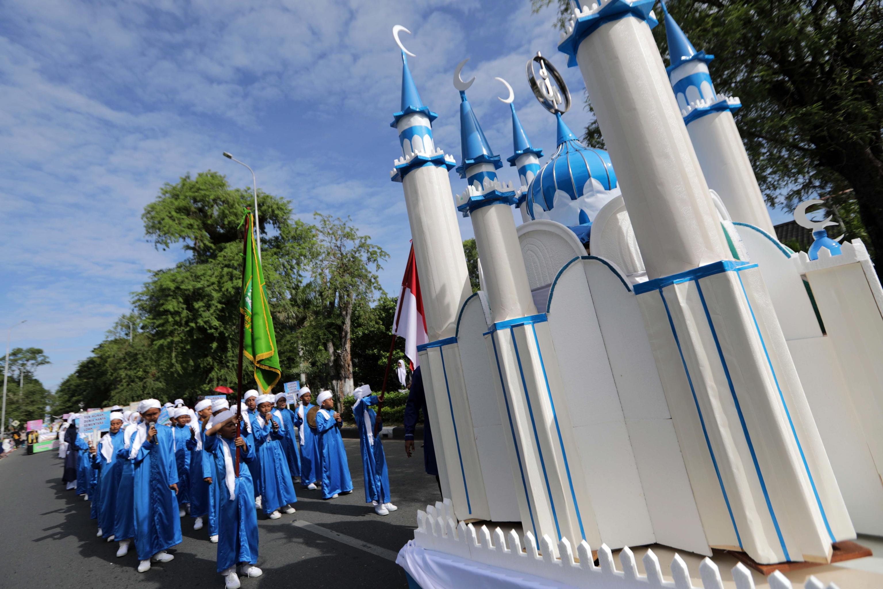 Alcuni studenti acehnesi trasportano la riproduzione di una moschea. L'azzurro dei finimenti è il colore del mese santo delle preghiere per l'Islam.