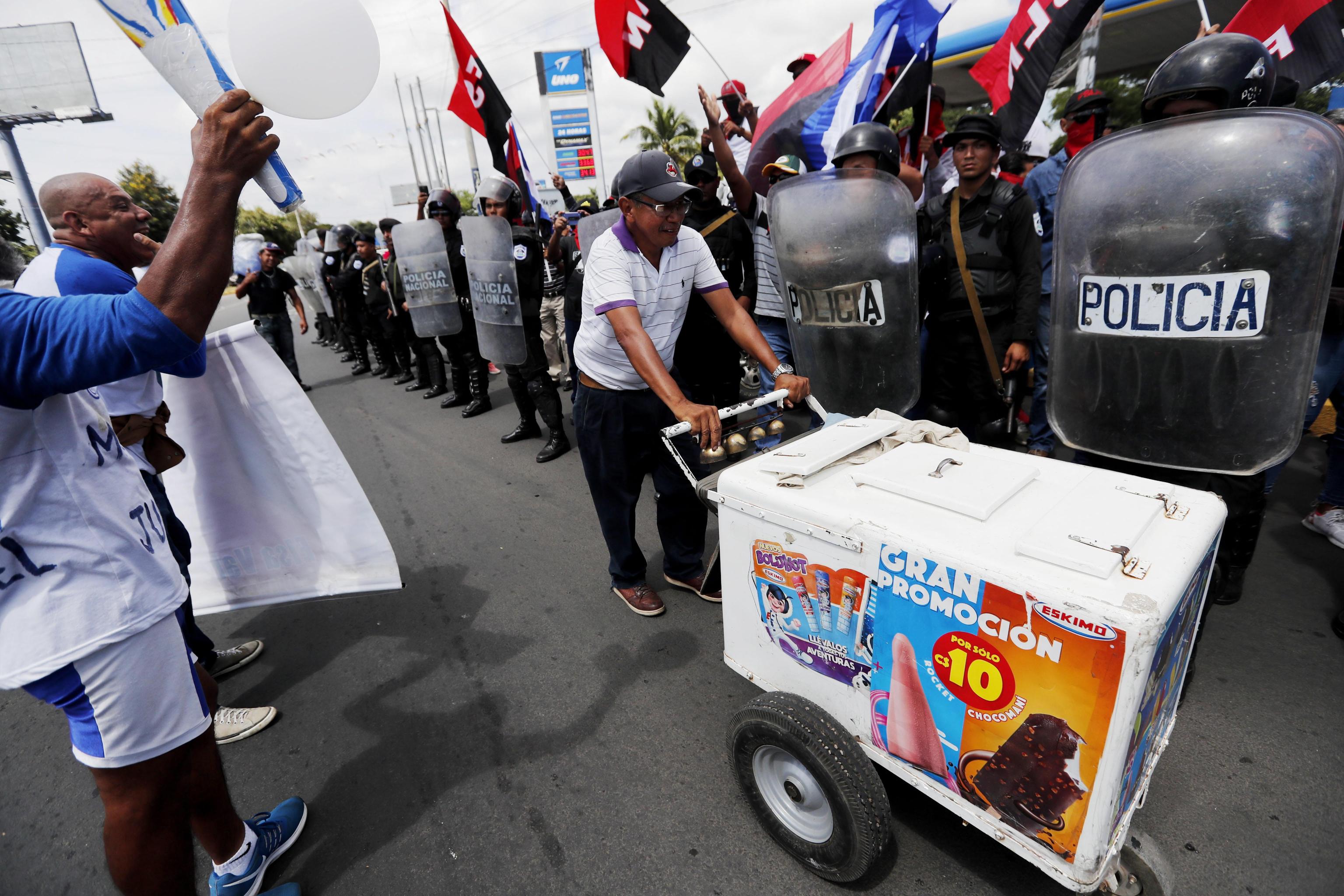 Un venditore di gelati passa tra i due gruppi di manifestanti contrapposti.