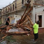 Persone camminano attraverso alcune abitazioni di Panama City devastate dall'urgano