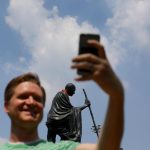 Un turista fotografa la statua con il suo smartphone