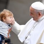 Bergoglio accarezza un bambino durante il giro in papamobile a San Pietro.
