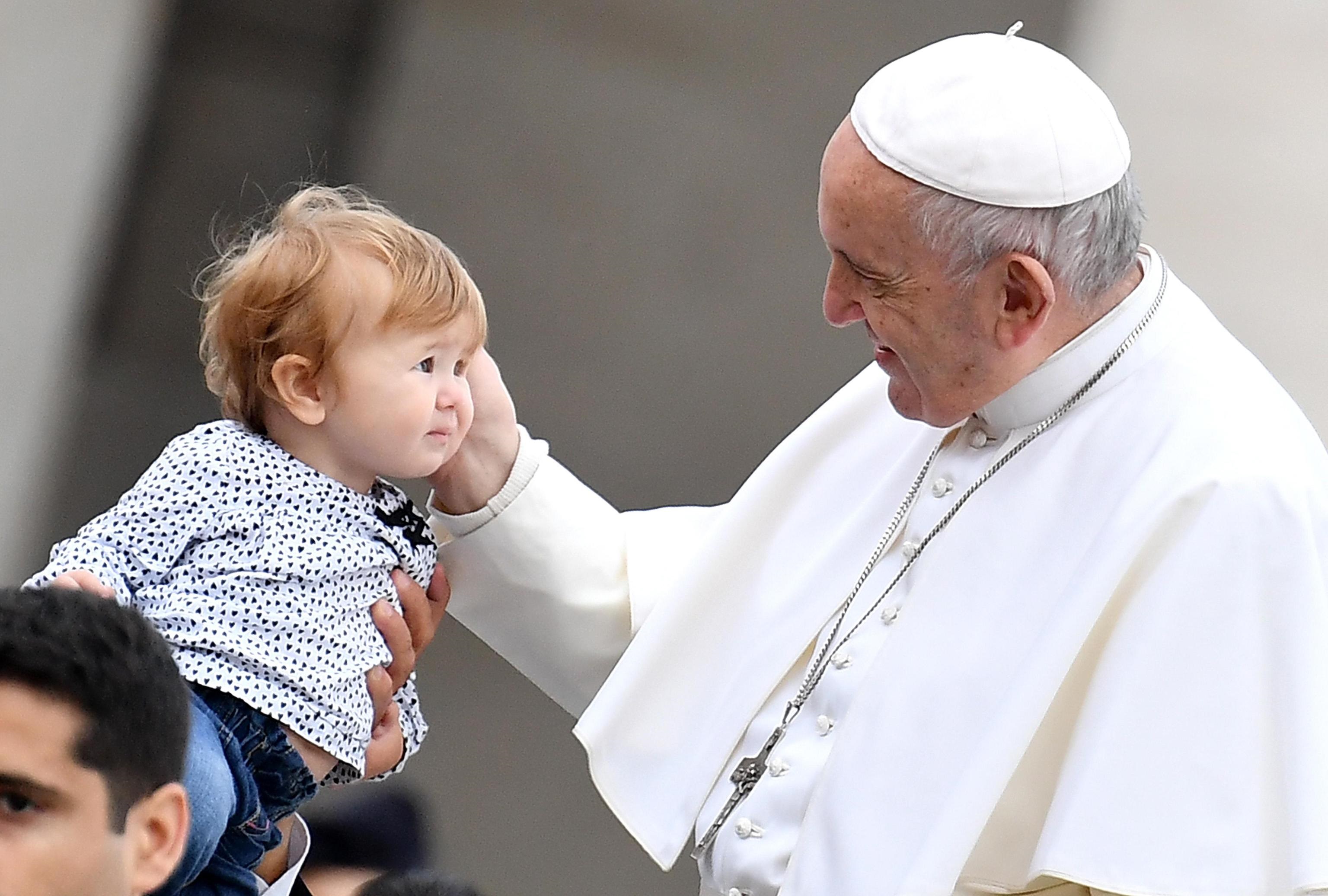 Bergoglio accarezza un bambino durante il giro in papamobile a San Pietro.